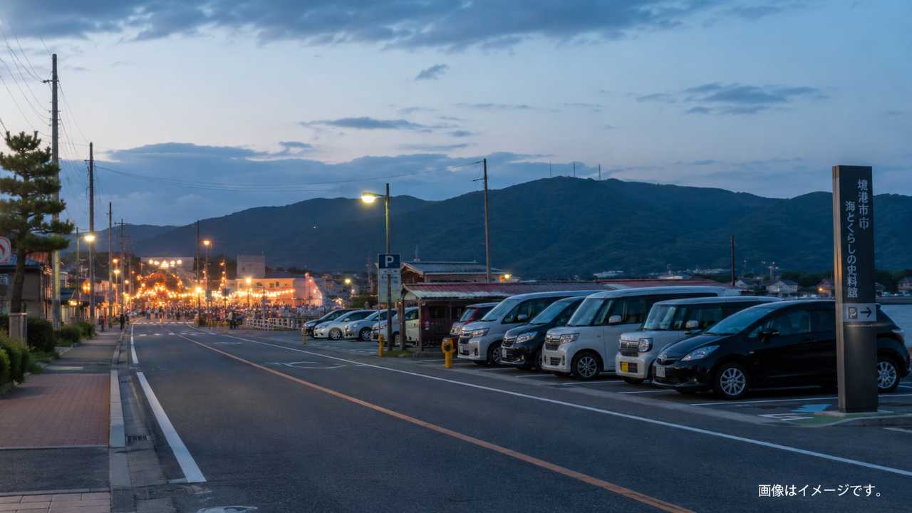 夕方の境港の道路と駐車場、遠くに祭り会場の明かりが見える