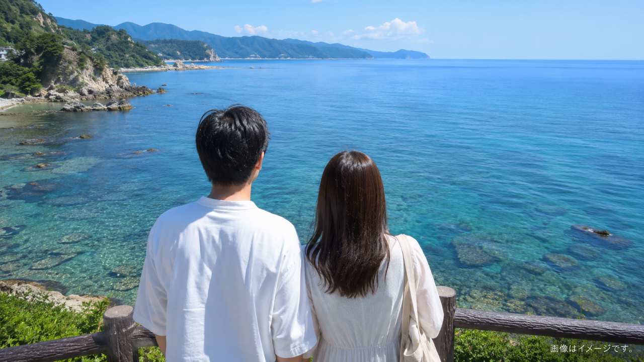 透明感のある海岸を眺めるカップルの後ろ姿。鳥取の海デートを連想させる爽やかな風景