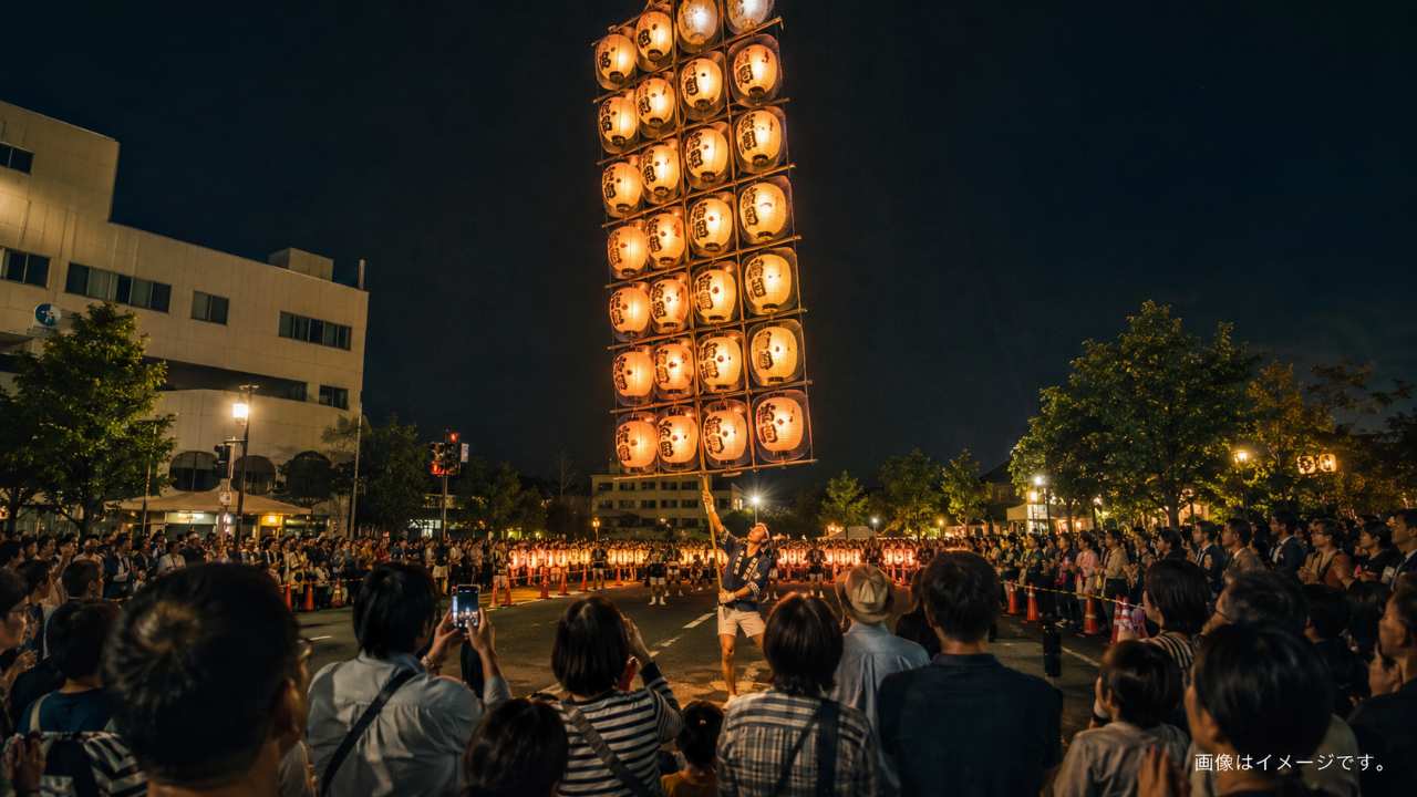 夜の米子市街地で、数多くの提灯が付いた高いがいな万灯を演者が堂々と掲げている場面