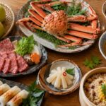 松葉がに、二十世紀梨、牛骨ラーメンなど鳥取県の代表的な食べ物を一卓に並べた構図