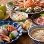 鳥取の海の幸や梨、牛骨ラーメンなど代表的な名物を食卓に並べた旅グルメのイメージ